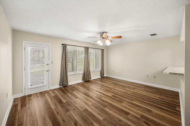 a view of an empty room with wooden floor and a window