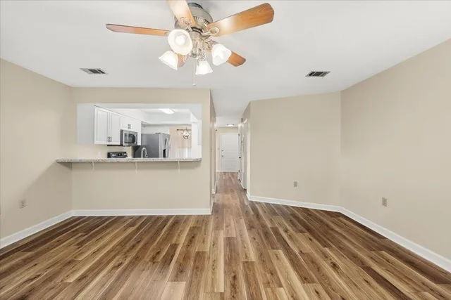 a view of kitchen and empty room with wooden floor