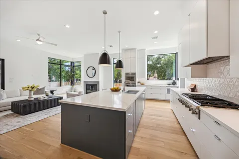 a kitchen with stainless steel appliances granite countertop a stove a sink a oven a dining table and chairs with wooden floor