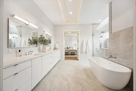 a large bathroom with a double vanity sink a large mirror and a bathtub