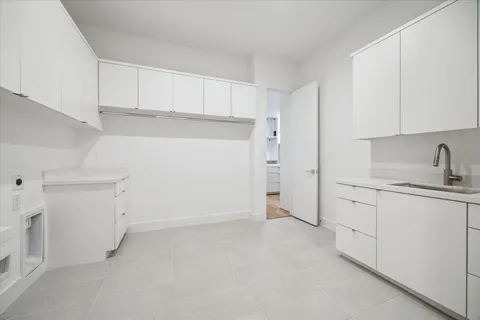 a kitchen with white cabinets and sink