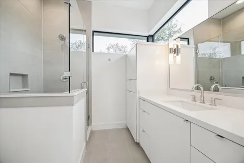 a bathroom with a double vanity sink mirror and shower