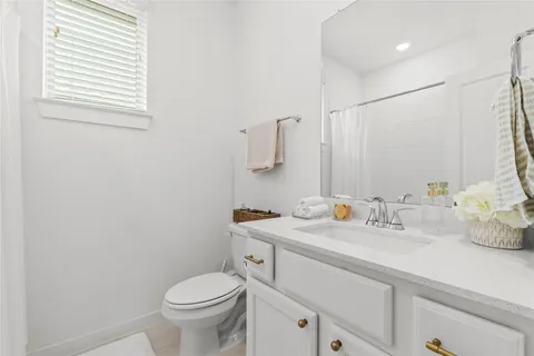a bathroom with a granite countertop toilet sink and mirror