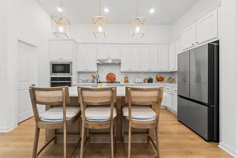 a kitchen with stainless steel appliances a dining table chairs refrigerator and microwave