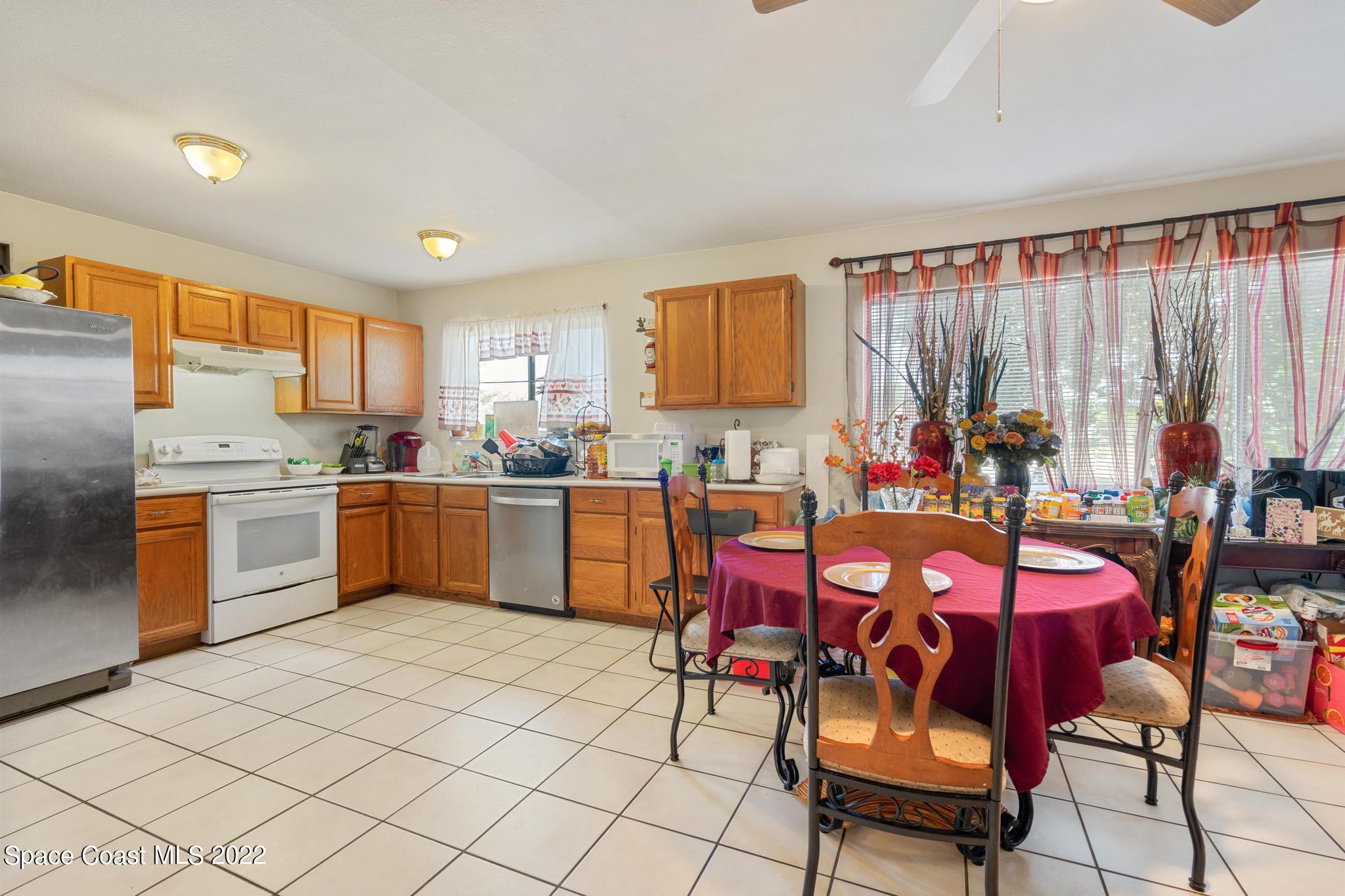 1148 Newbern Street Northeast Palm Bay, FL 32905 - Photo 11 of 38 a kitchen with a sink dining table and chairs