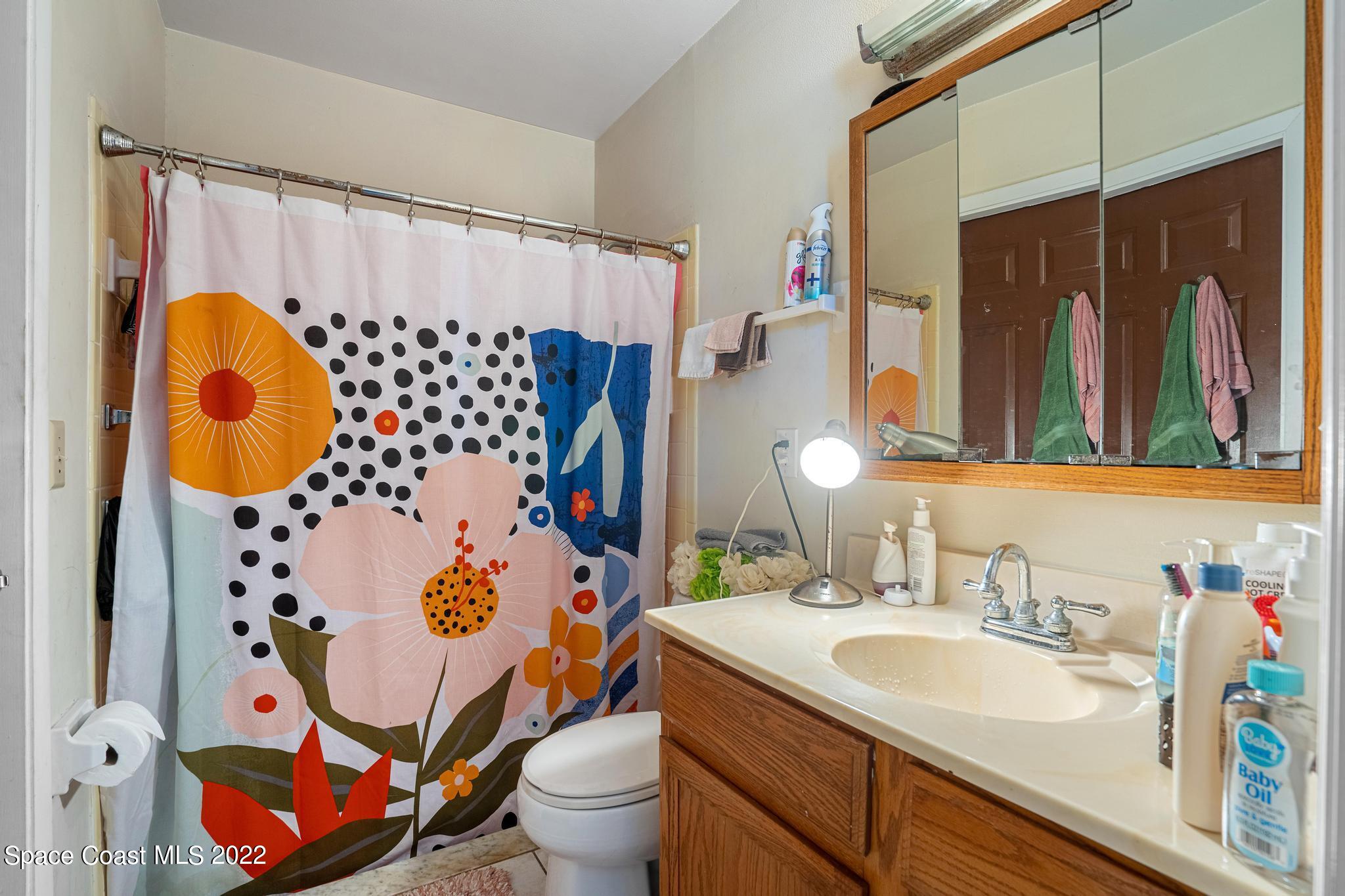 1148 Newbern Street Northeast Palm Bay, FL 32905 - Photo 17 of 38 a bathroom with a sink toilet and shower curtain