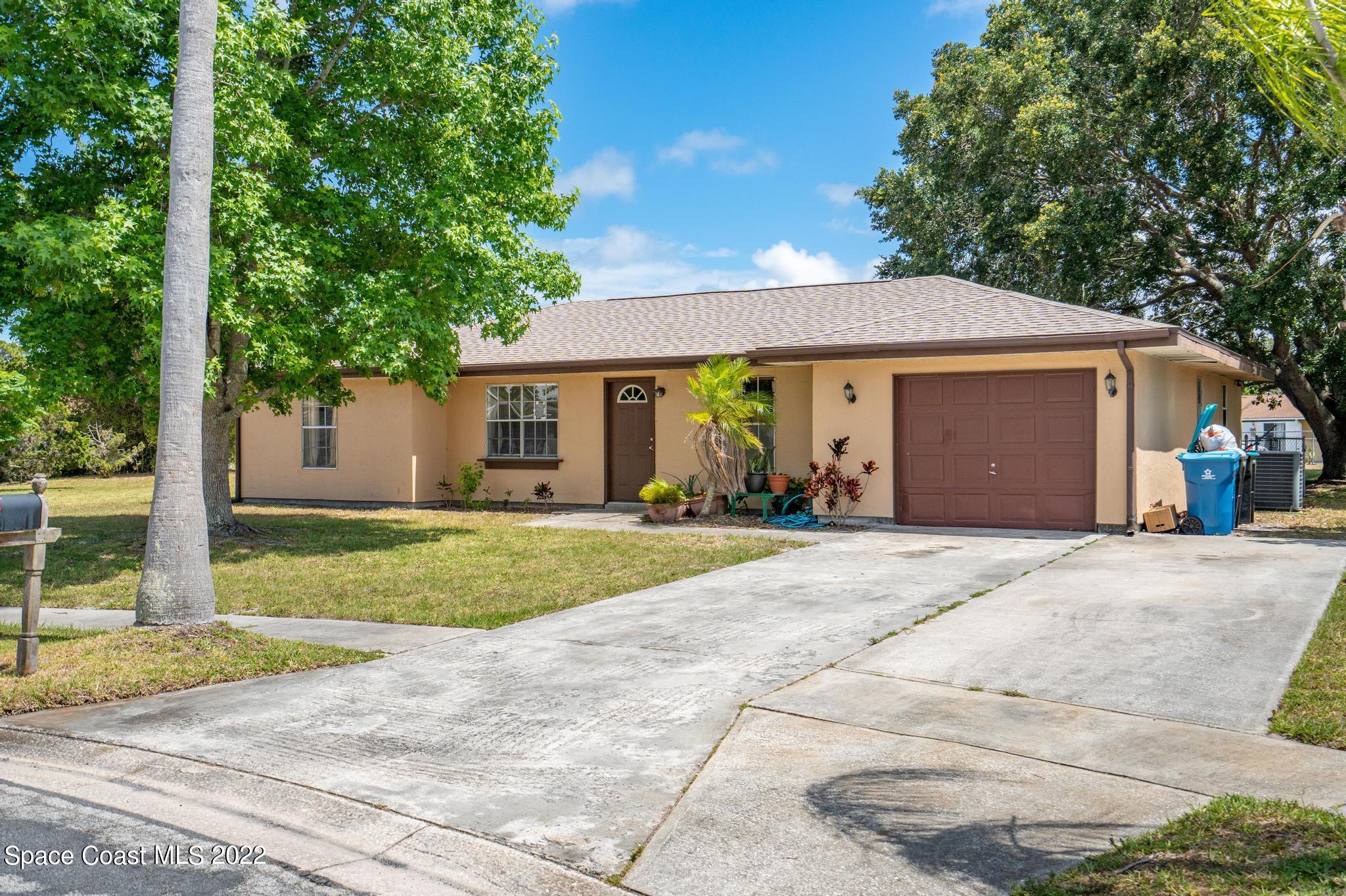 1148 Newbern Street Northeast Palm Bay, FL 32905 - Photo 21 of 38 a front view of a house with a garden and trees