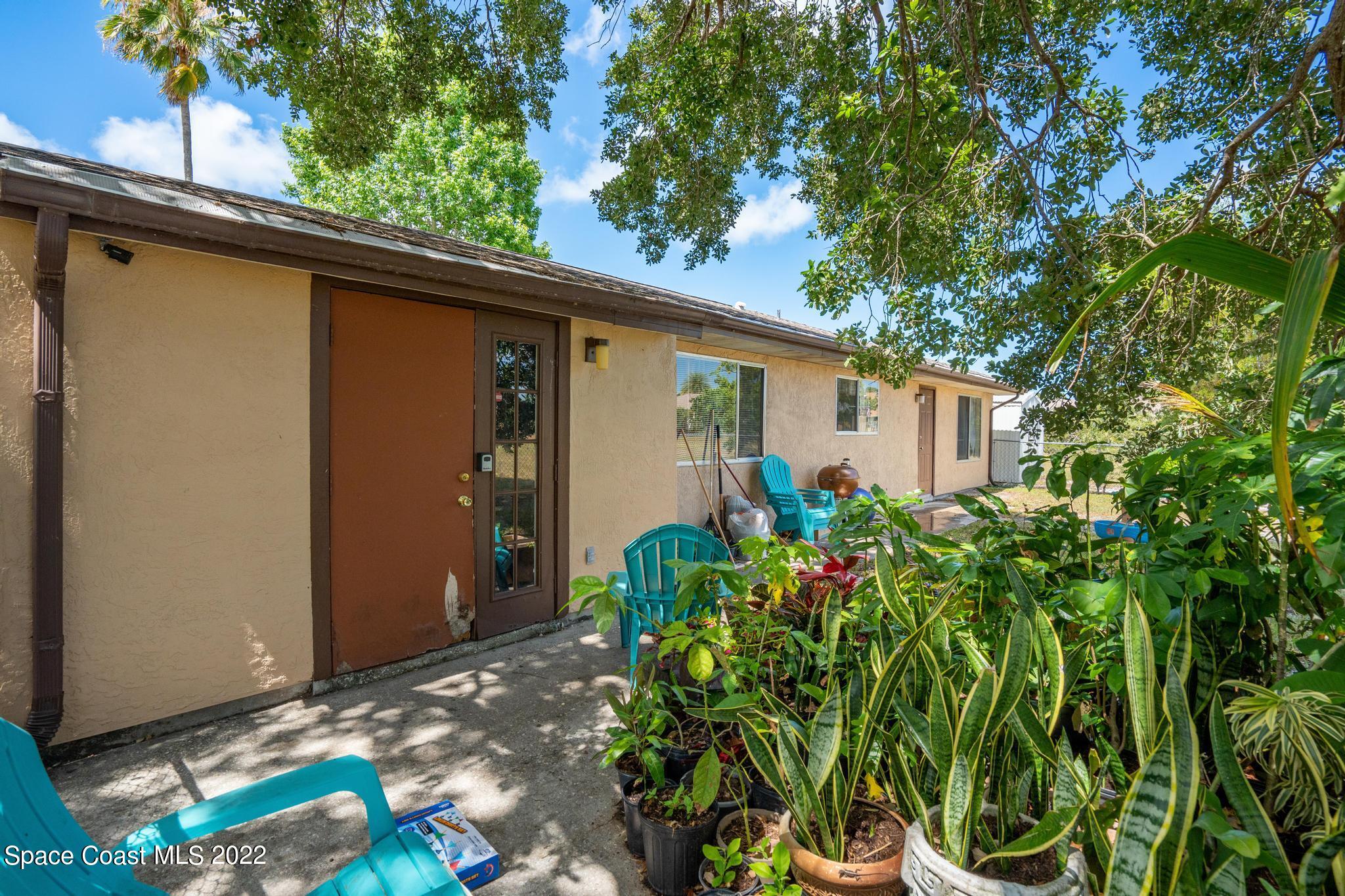1148 Newbern Street Northeast Palm Bay, FL 32905 - Photo 27 of 38 a backyard of a house with large trees and plants