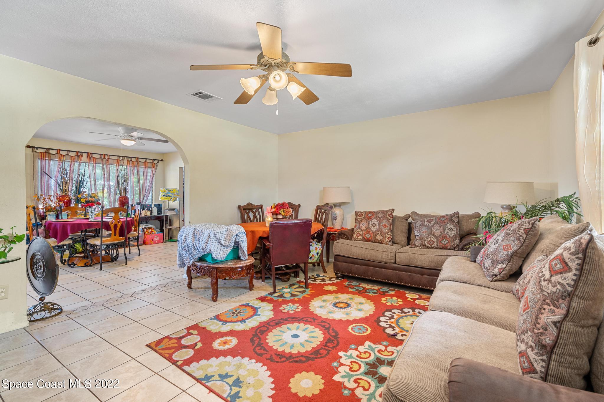 1148 Newbern Street Northeast Palm Bay, FL 32905 - Photo 7 of 38 a living room with furniture a chandelier and a dining table