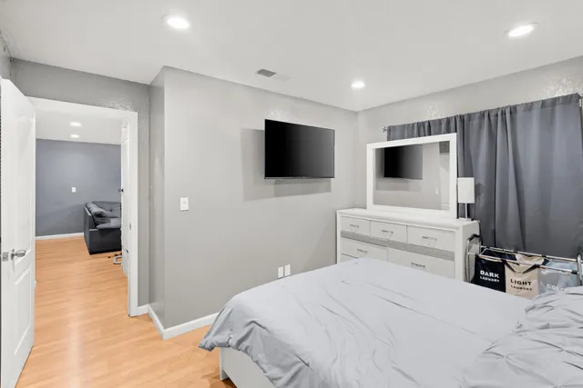 a bedroom with a bed and a flat tv screen on wall