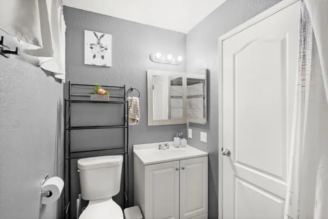 a bathroom with a toilet sink vanity and mirror