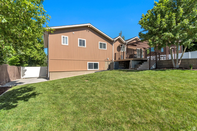 9832 Falconhurst Drive Sandy, UT 84092 - Photo 24 of 29 Expansive sloped lawn with a multi-level deck featuring a pergola, modern railing, and integrated staircase
