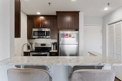 a kitchen with kitchen island granite countertop a sink stainless steel appliances and cabinets