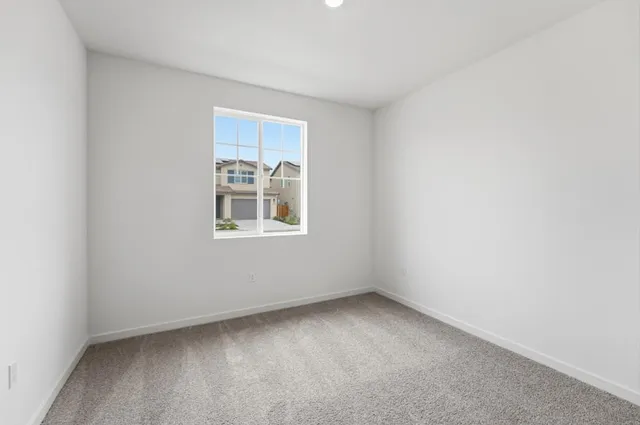 a view of an empty room with wooden floor and windows