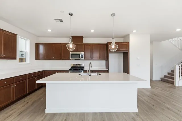 a large kitchen with stainless steel appliances kitchen island a large counter top a sink a stove and a refrigerator