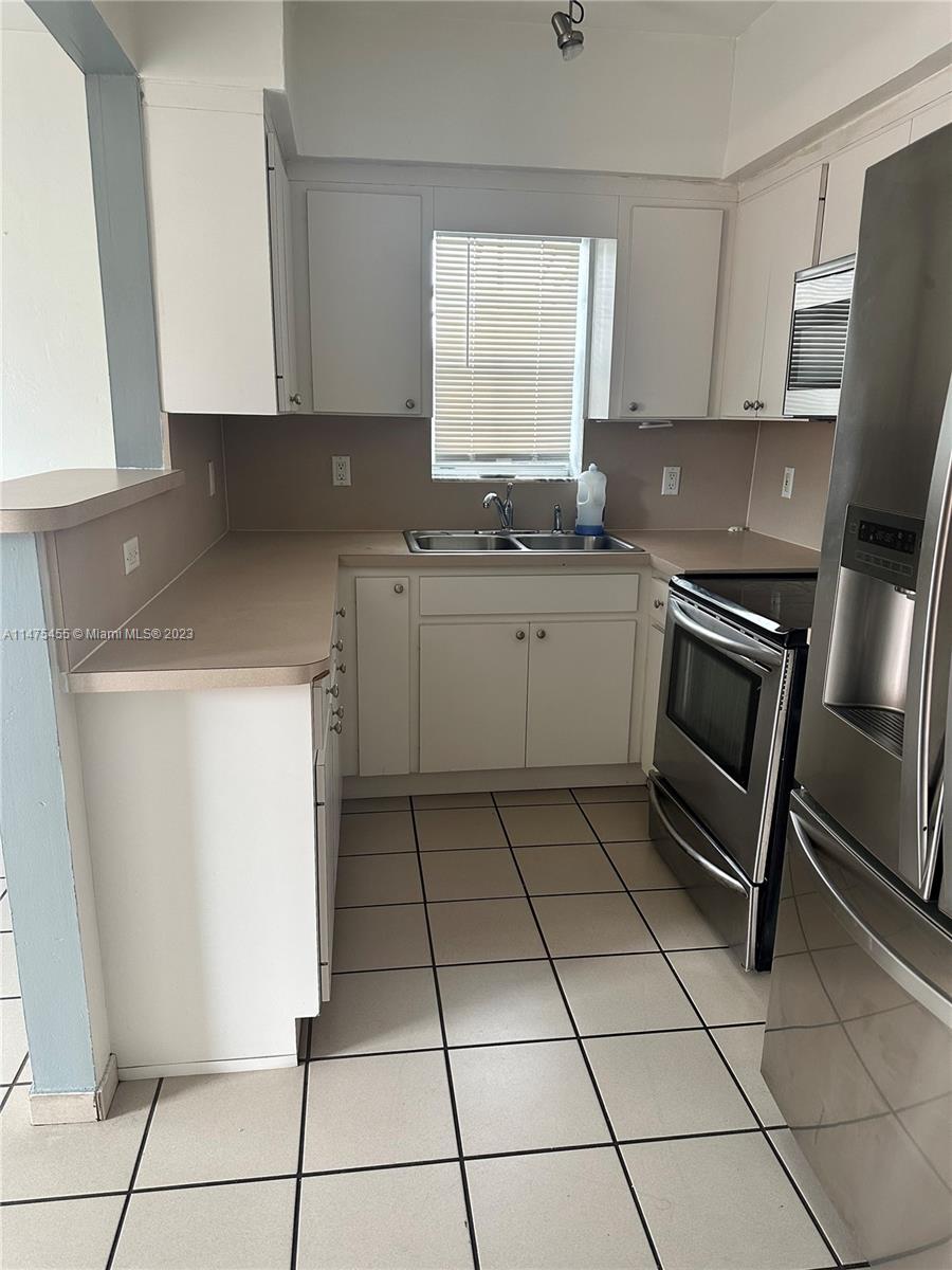 7075 Southwest 14th Street, Unit 1 Miami, FL 33144 - Photo 6 of 10 a kitchen with a sink a stove top oven and cabinets
