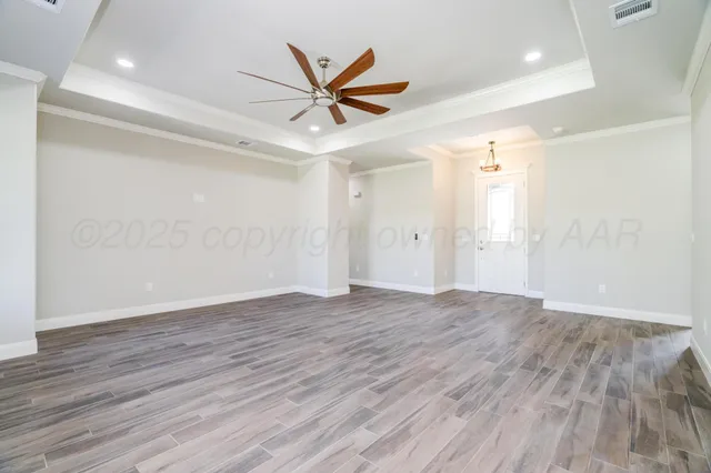 an empty room with wooden floor and a ceiling fan