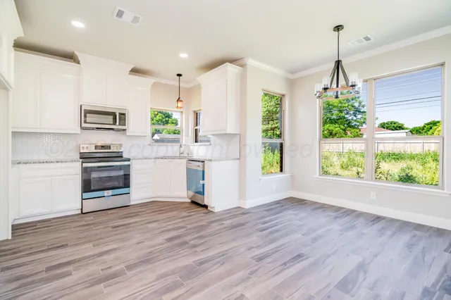 a kitchen with stainless steel appliances a stove top oven and a wooden floor