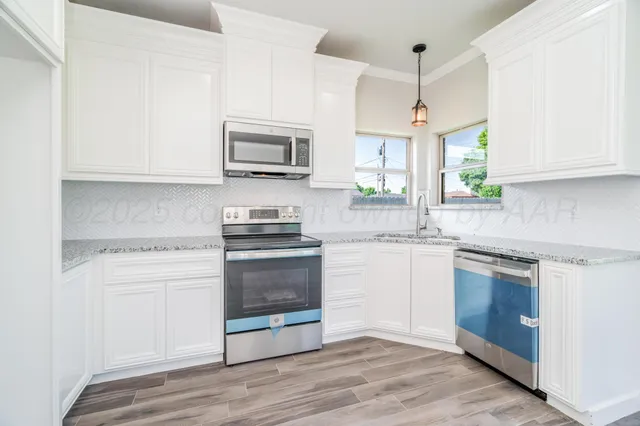 a kitchen with stainless steel appliances granite countertop a stove a sink and a microwave