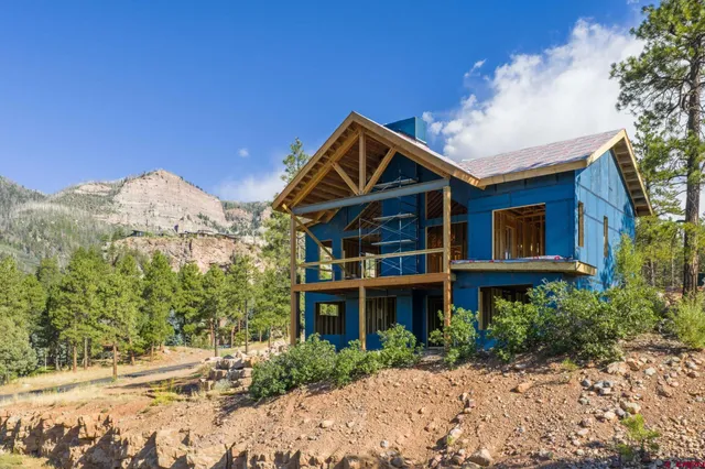 a front view of a house with a yard and mountain view in back
