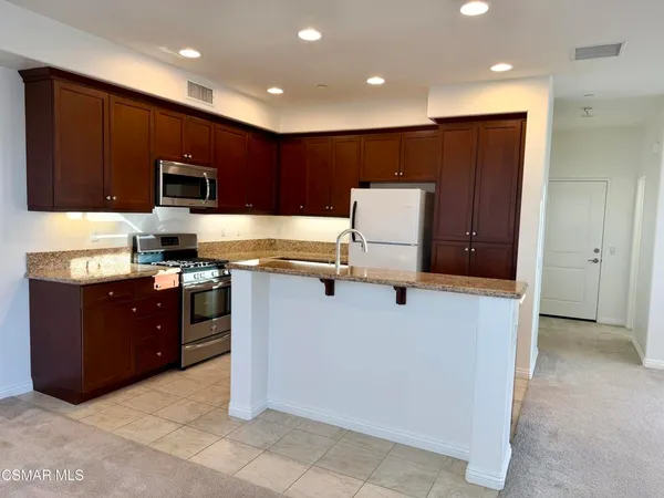 a kitchen with stainless steel appliances a refrigerator and a stove top oven