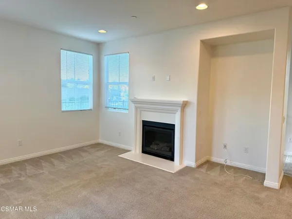 an empty room with windows and fireplace