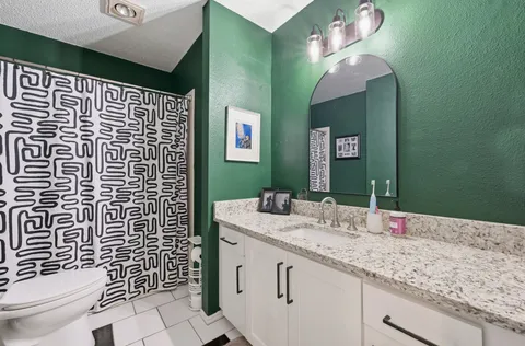 a bathroom with a granite countertop sink toilet and shower