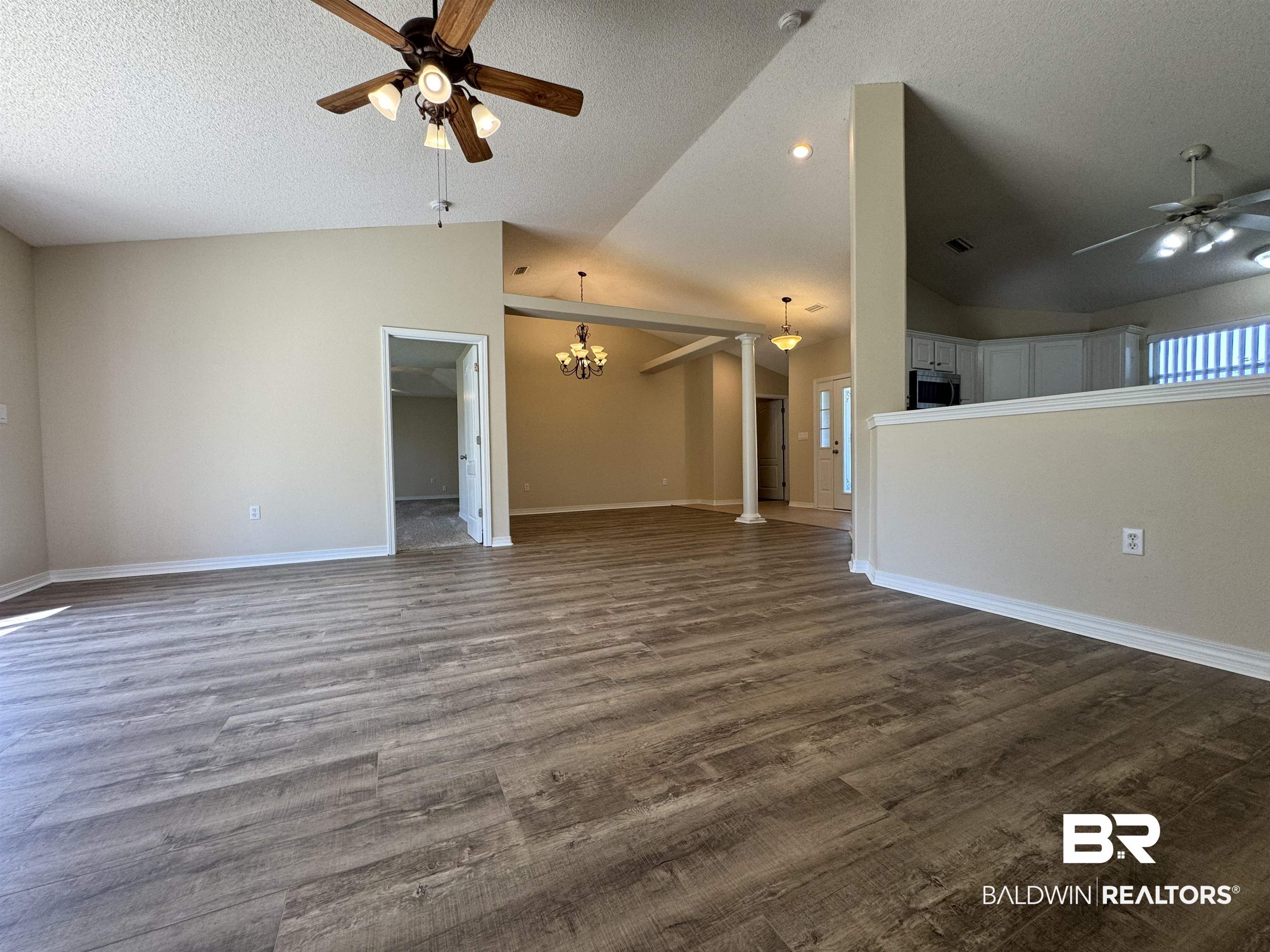 32769 Arbor Ridge Circle Lillian, AL 36549 - Photo 3 of 36 Unfurnished living room featuring ceiling fan with notable chandelier, a textured ceiling, lofted ceiling, and dark hardwood / wood-style flooring