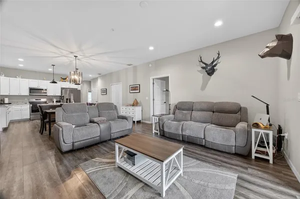 a living room with furniture a kitchen view and a chandelier