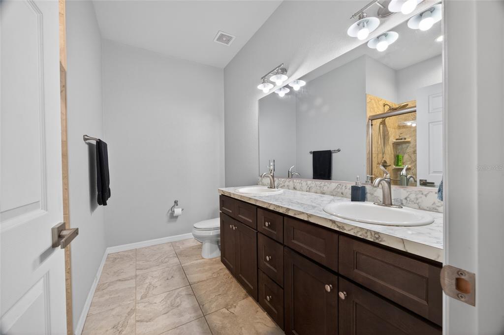 3415 West Anthony Road, Unit 303 Ocala, FL 34475 - Photo 19 of 29 a bathroom with a granite countertop sink a toilet and a mirror