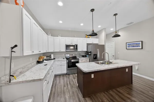 a large kitchen with granite countertop a sink a counter top space appliances and cabinets