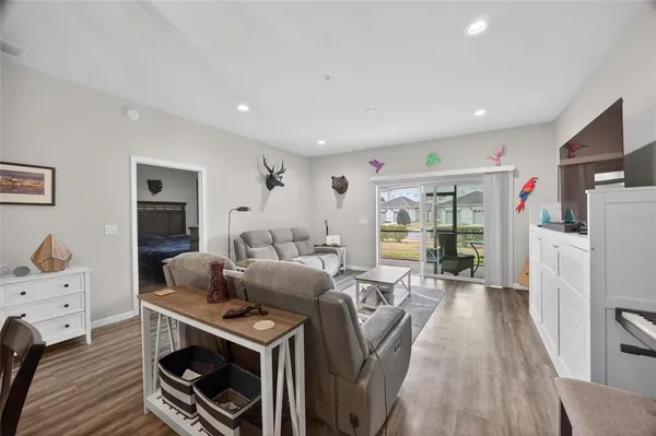 a living room with furniture a flat screen tv and a refrigerator