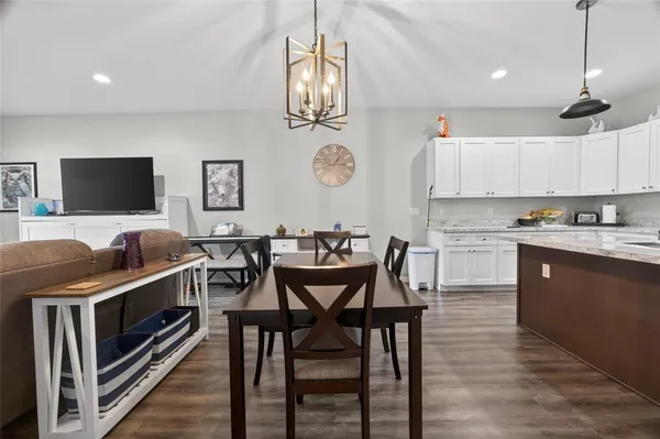a kitchen with stainless steel appliances granite countertop a stove top oven a sink a dining table and chairs with wooden floor