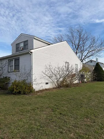 a backyard of a house with plants and large tree