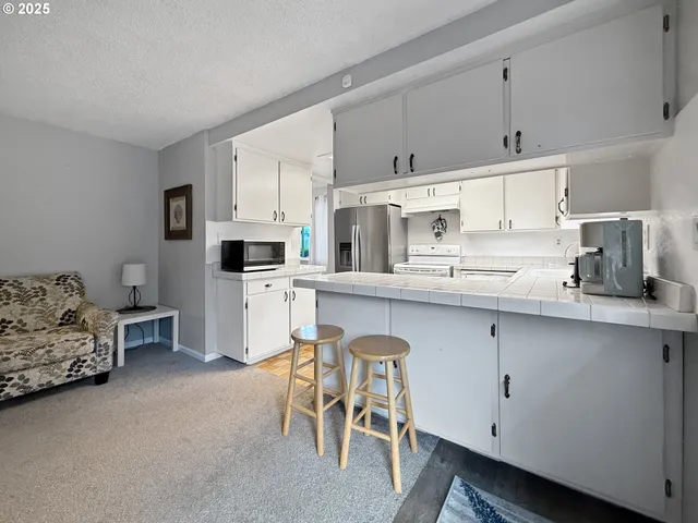 a kitchen with stainless steel appliances white cabinets and a couch