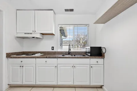 a kitchen with granite countertop a sink and a white cabinets