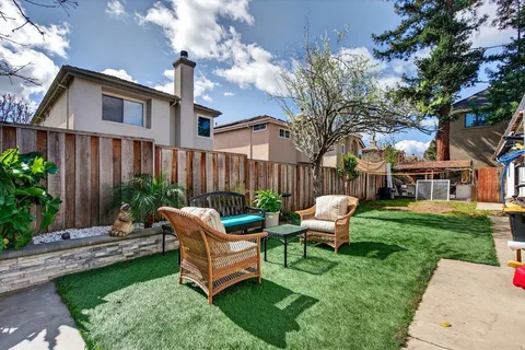 a view of a patio with couches table and chairs with plants and wooden fence