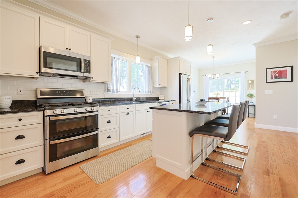 47 Compass Point Drive, Unit 47 Douglas, MA 01516 - Photo 7 of 32 a kitchen with stainless steel appliances kitchen island granite countertop a stove a sink and white cabinets