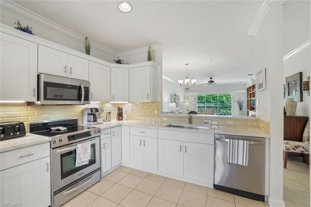 3047 Horizon Lane, Unit 1908 Naples, FL 34109 - Photo 5 of 17 Kitchen with stainless steel appliances, white cabinetry, sink, tasteful backsplash, and ornamental molding