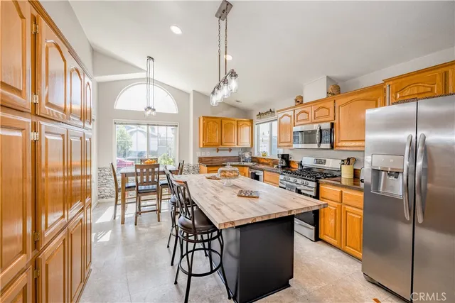 a kitchen with a refrigerator a stove a sink and a dining table with wooden floor