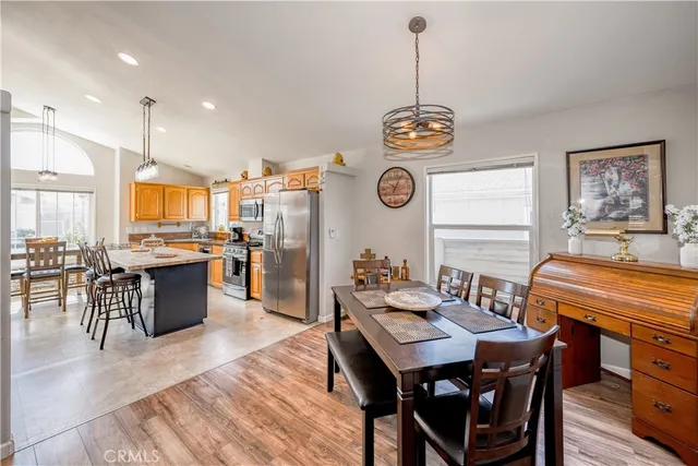 a dining room with wooden floor a chandelier a wooden table and chairs