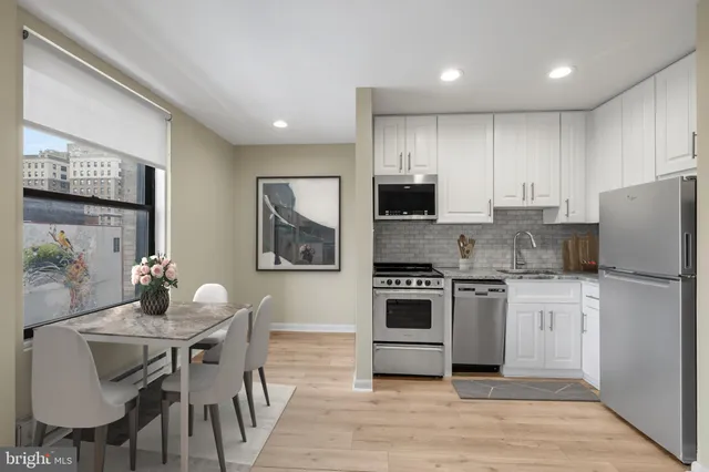 a kitchen with a refrigerator a stove a microwave oven a dining table and chairs with wooden floor