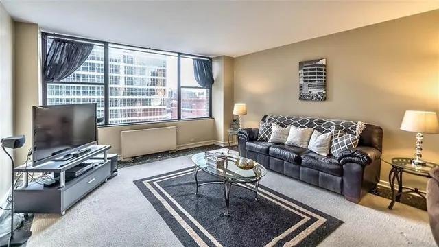 a living room with furniture a flat screen tv and a window