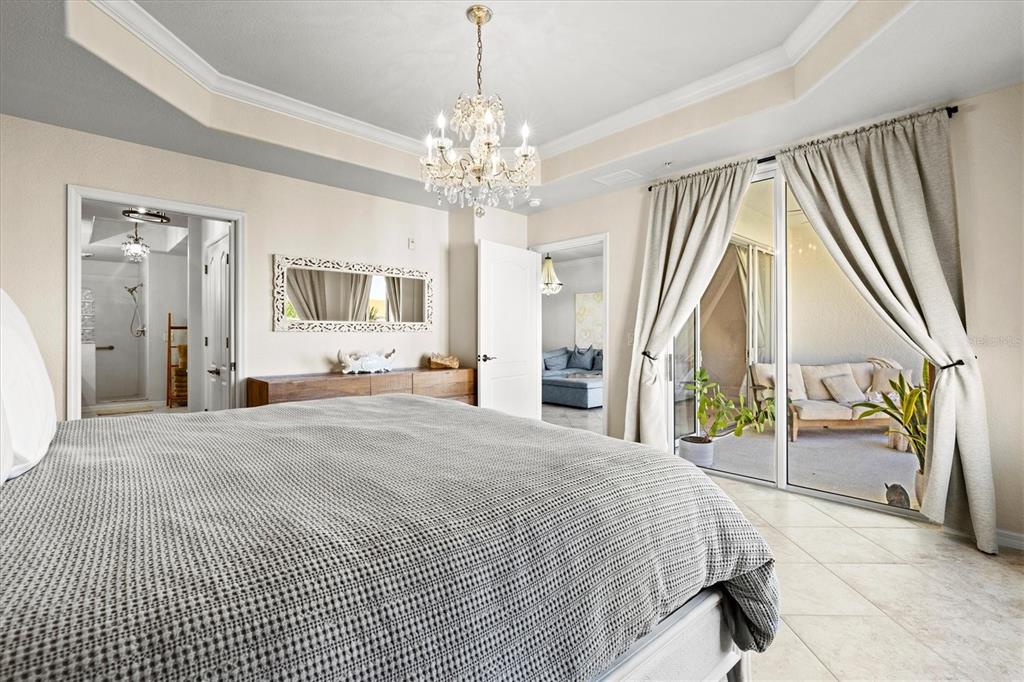 1000 San Lino Circle, Unit 1032 Venice, FL 34292 - Photo 26 of 88 a spacious bedroom with a large bed and a chandelier