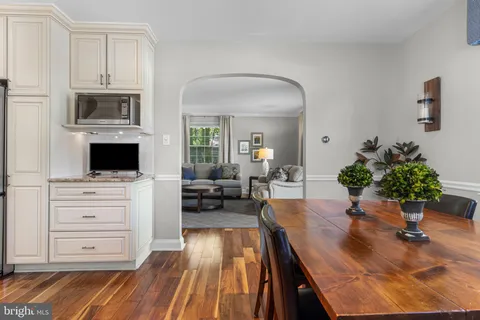 a kitchen with stainless steel appliances kitchen island granite countertop a refrigerator a stove and white cabinets with wooden floor
