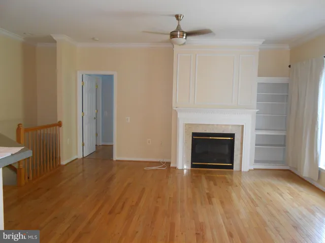 a view of an empty room with wooden floor fireplace and a window