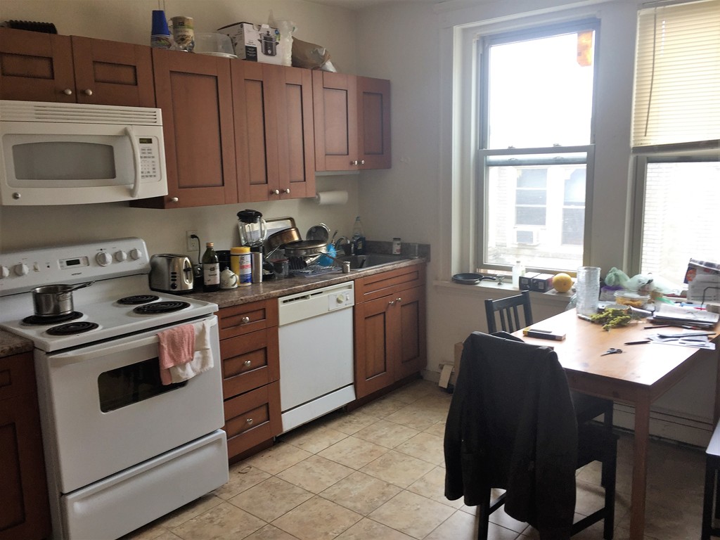24 Ransom Road, Unit 9 Boston, MA 02135 - Photo 2 of 4 a kitchen with a stove a sink and white cabinets