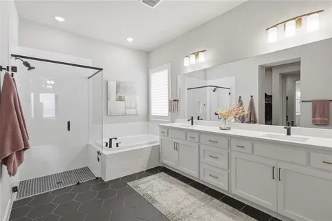 a spacious bathroom with double vanity a mirror a bathtub and shower