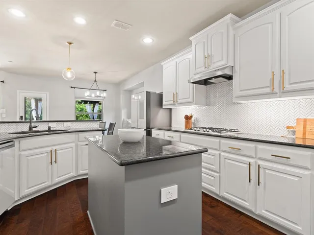 a kitchen with white cabinets sink and stove