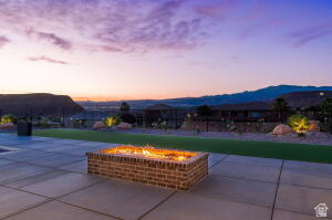 1141 East Lost Ridge Drive Washington, UT 84780 - Photo 16 of 108 Expansive outdoor patio featuring a built-in brick fire pit, large format concrete pavers, artificial turf, and a mountain backdrop